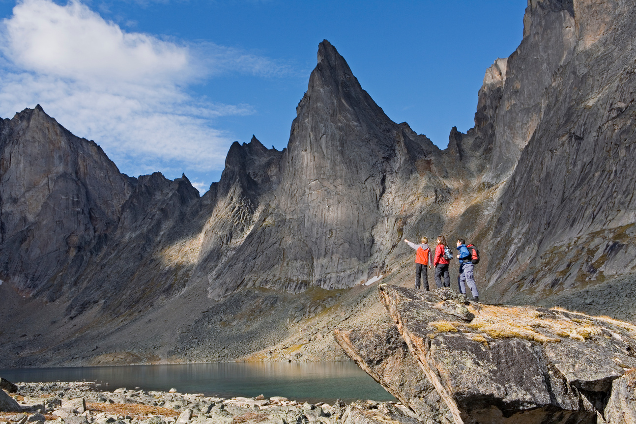 three people hiking near jagged mountains