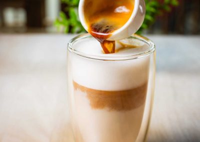 espresso being poured into a glass of milk