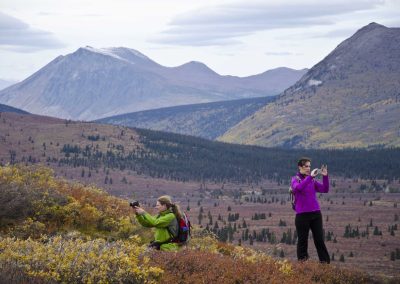 two people taking pictures of a mountainous terrain