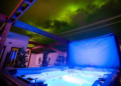 aurora borealis in the night sky, lighted jacuzzi on the foreground
