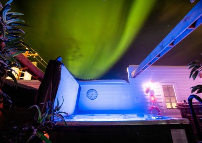aurora borealis in the night sky, lighted jacuzzi on the foreground