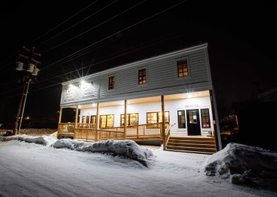 white, wooden building on a snow-covered road at night