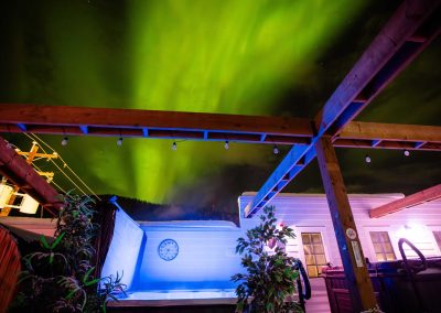 aurora borealis in the night sky, lighted jacuzzi on the foreground